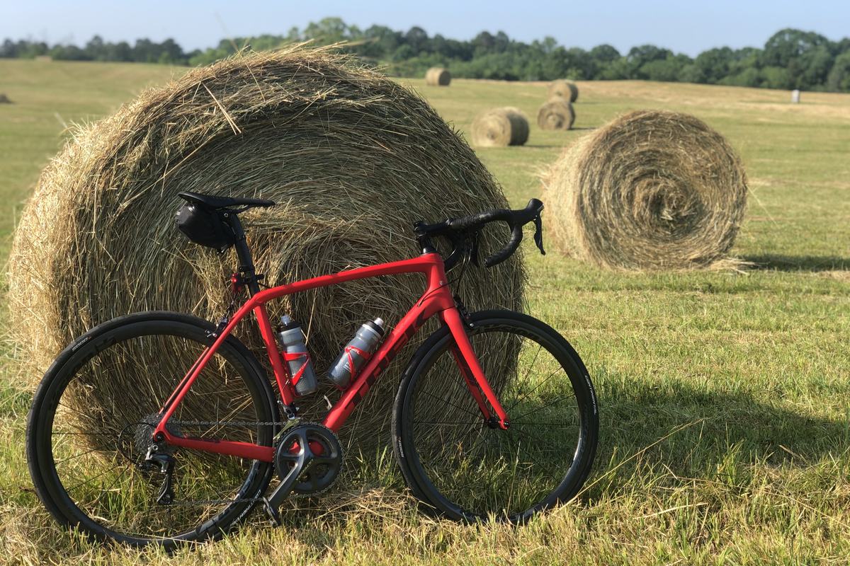 The red Trek Domane road bike leaning against a round hay bale