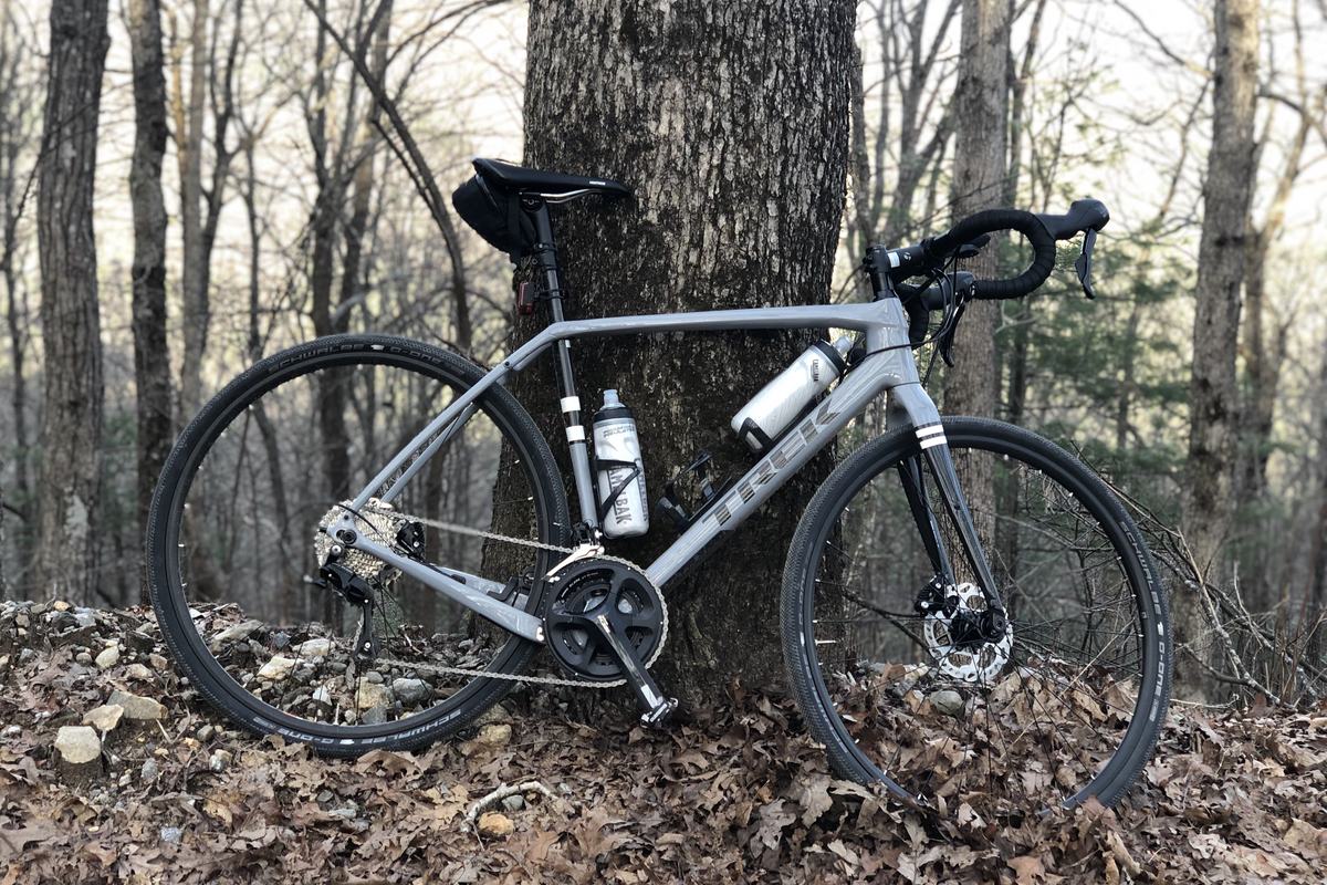 The grey Trek Checkpoint gravel bike against a tree in bare winter woods