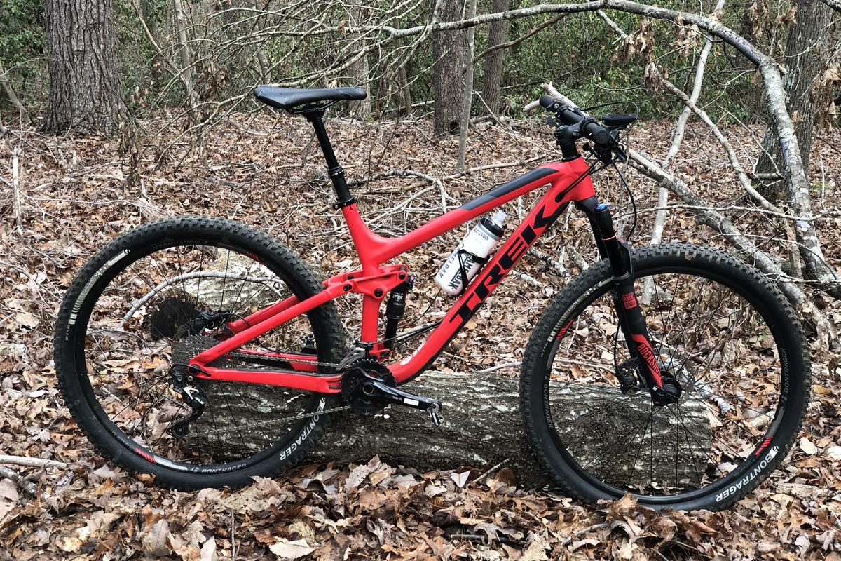 The red Trek Fuel EX full-suspension bike on a leaf-covered trail