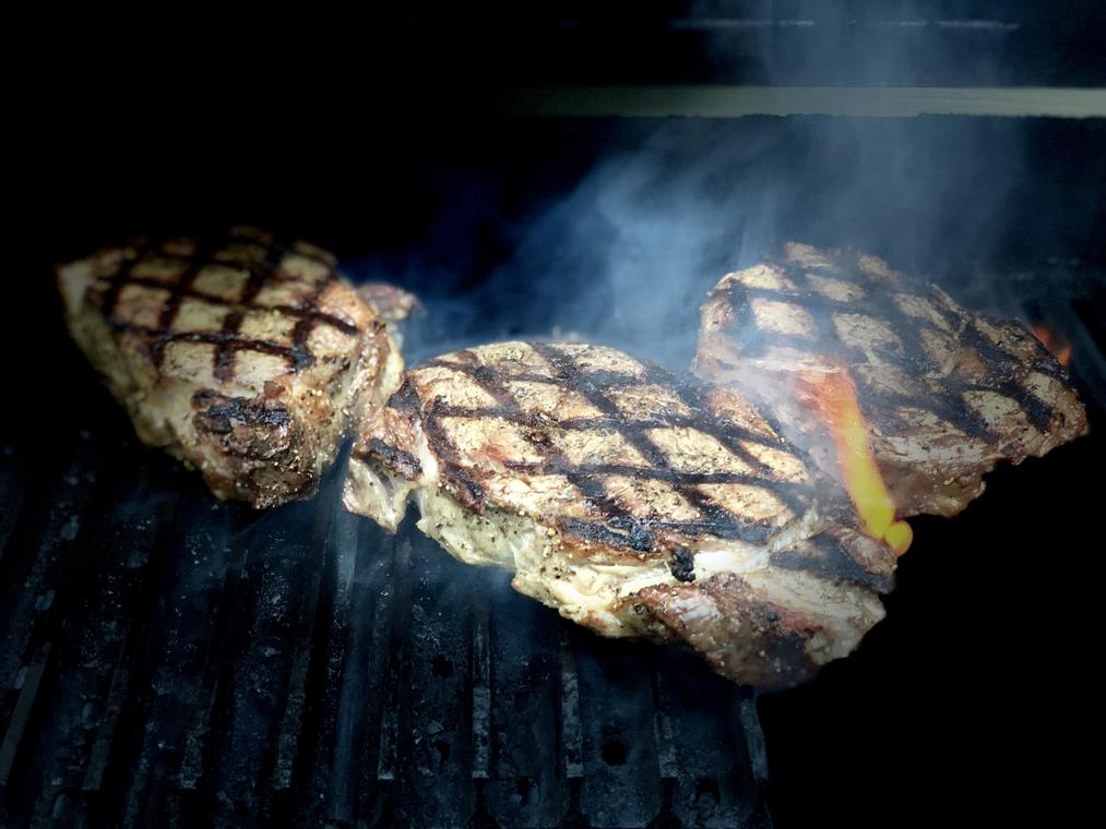 Grill-marked steaks with smoke coming off the grate