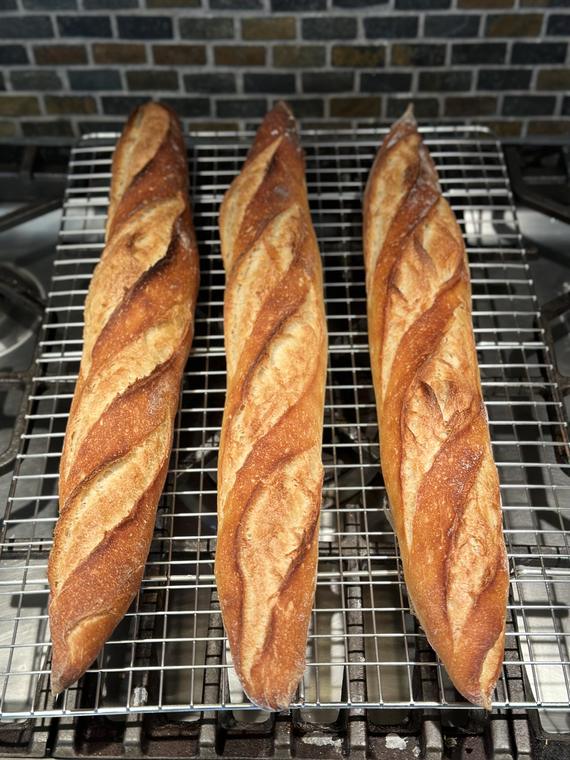 Three baguettes cooling on a rack