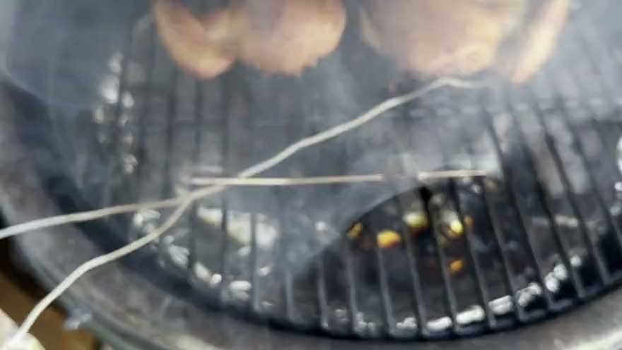 The lid comes off the Big Green Egg and the smoke clears to show two spatchcocked chickens on the grate