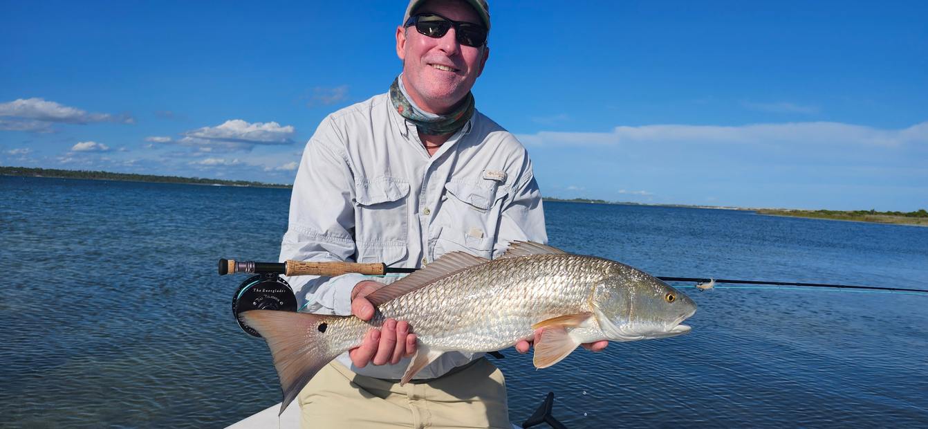 Holding a redfish on the boat, fly rod alongside
