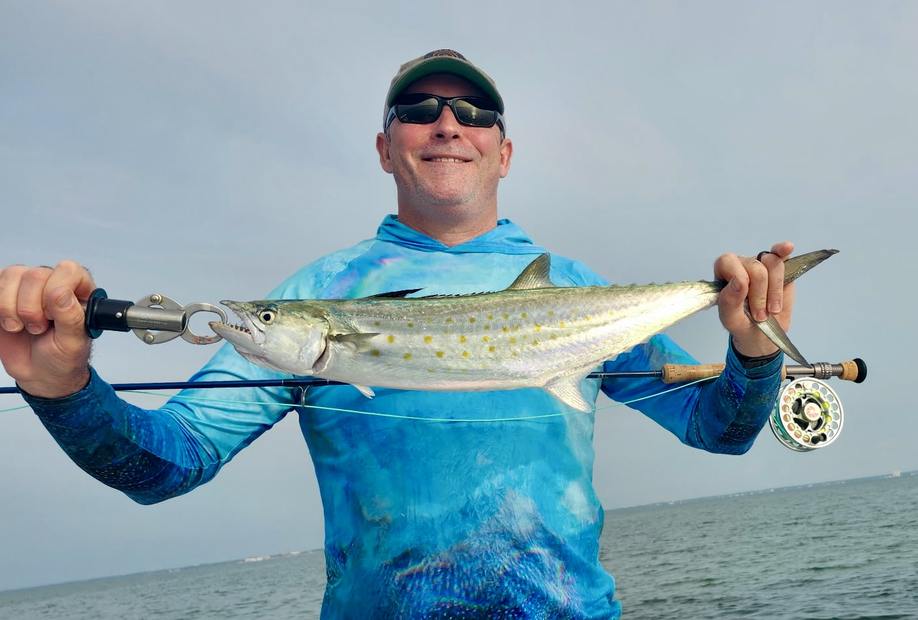 A Spanish mackerel held up against a blue sky