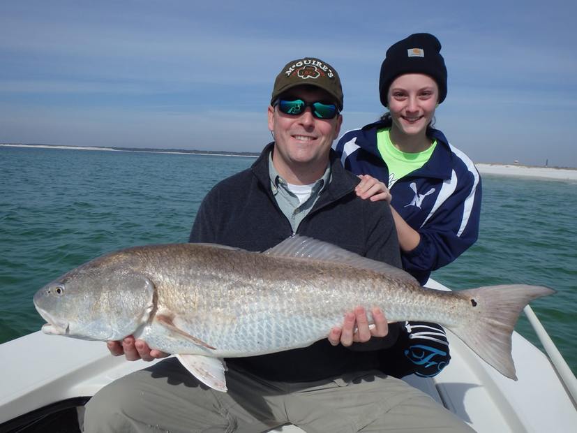 Two people on the boat holding a redfish between them