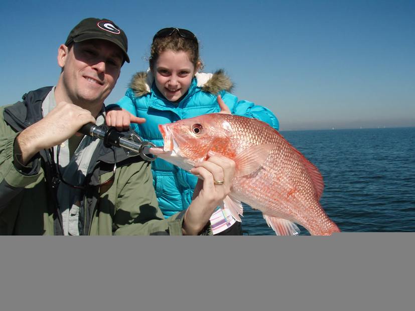 Holding a red snapper on deck with a young angler