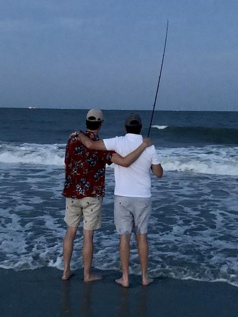 Two people casting into the surf from the beach