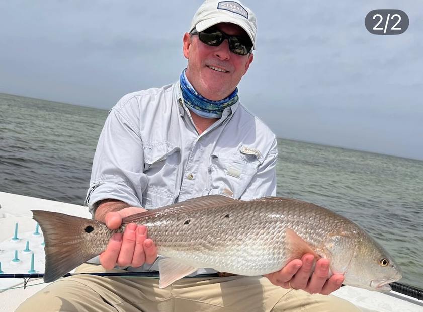 A redfish held across the lap on the poling platform