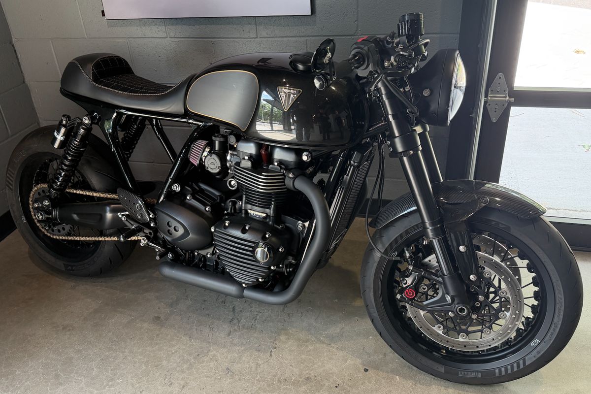 The custom Triumph Thruxton R cafe racer: gloss black tank with a gold pinstripe, quilted seat, spoked wheels