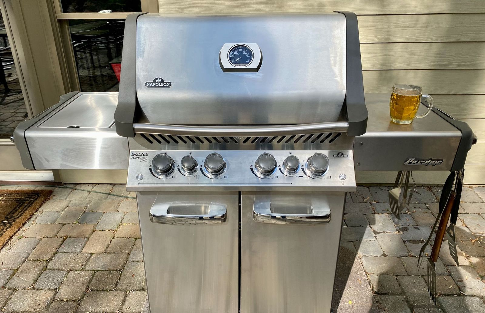 The Napoleon Prestige 500 on the patio, lid closed, a beer on the shelf