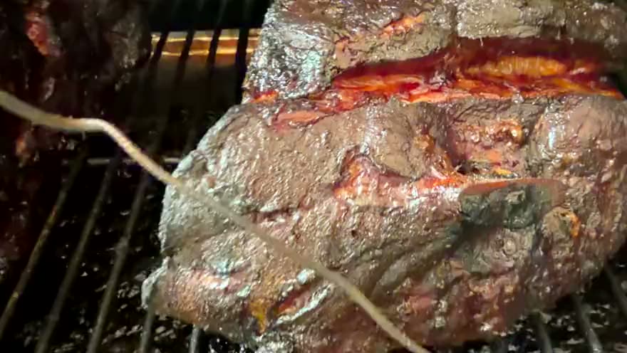 Two pork butts on the recteq grate with probes in, the fire glowing underneath